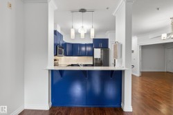 Kitchen featuring blue cabinetry, stainless steel appliances, a white countertop, under-cabinet lighting, and suspended pendant lighting - 