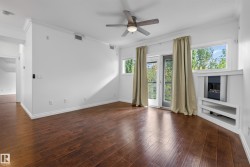 Wood-finish flooring, crown molding, built-in fireplace, ceiling fan, and a glass-paned door leading to a balcony - 