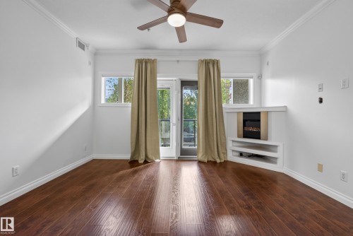 Wood-finish flooring throughout, complemented by crown molding and a ceiling fan with integrated lighting - #210 10121 80 Av Nw, Edmonton, AB 