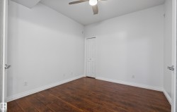 Wood-finish flooring, white walls, white trim, bi-fold closet door, and ceiling fan - 