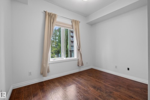 Crisp white walls, wood-finish flooring, and a window with white trim - #210 10121 80 Av Nw, Edmonton, AB 