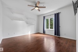 Wood-finish flooring, ceiling fan with integrated lighting, built-in shelving, and white walls - 