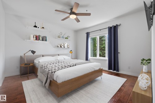 Wood-finish flooring with crisp white walls, a ceiling fan with integrated lighting, built-in wall shelving, and a large window - #210 10121 80 Av Nw, Edmonton, AB 