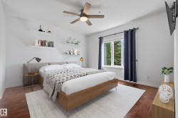 Wood-finish flooring with crisp white walls, a ceiling fan with integrated lighting, built-in wall shelving, and a large window - 