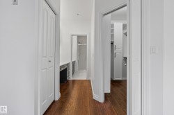 Hardwood-finish flooring extending through the hallway, white bi-fold closet doors, built-in vanity with countertop, and an additional built-in storage unit - 