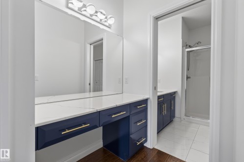 Floating vanity with a quartz countertop, full-width mirror, and chrome vanity lighting - #210 10121 80 Av Nw, Edmonton, AB 