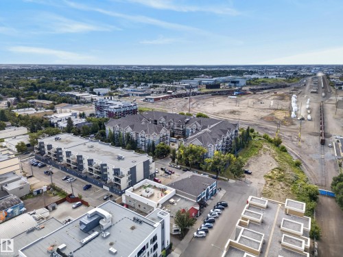 Aerial perspective of a mixed-use urban landscape featuring residential buildings, commercial structures, and a prominent transportation corridor - #210 10121 80 Av Nw, Edmonton, AB 