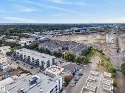 Aerial perspective of a mixed-use urban landscape featuring residential buildings, commercial structures, and a prominent transportation corridor - 
