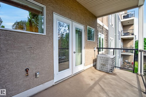 Private balcony with glass panel railing and stucco exterior - #210 10121 80 Av Nw, Edmonton, AB 