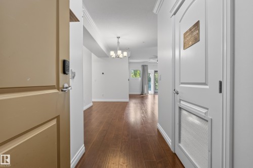 Wood-finish flooring throughout, crown molding details, and a modern chandelier - #210 10121 80 Av Nw, Edmonton, AB 