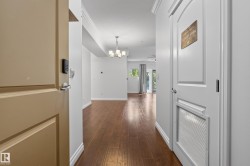 Wood-finish flooring throughout, crown molding details, and a modern chandelier - 