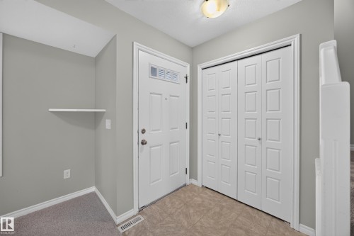 Entryway featuring a white paneled door with glass inserts, neutral-toned tiled flooring, and a built-in closet with paneled bifold doors - 483 Watt Boulevard Sw, Edmonton, AB 