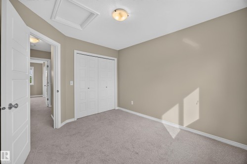 Neutral tone wall paint, light gray carpeting, white bi-fold closet doors, white trim, and a flush mount ceiling light - 483 Watt Boulevard Sw, Edmonton, AB 