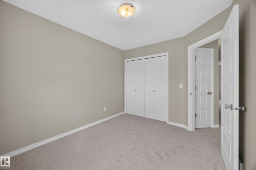 Spacious bedroom with neutral carpeting, dual closets with white bi-fold doors, recessed ceiling lighting, and pristine white trim throughout - 483 Watt Boulevard Sw, Edmonton, AB 