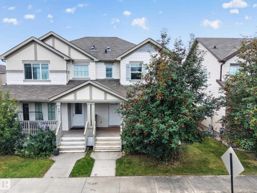 Two-story townhome with a peaked roofline, white siding, a covered porch, and an attached garage - 483 Watt Boulevard Sw, Edmonton, AB 