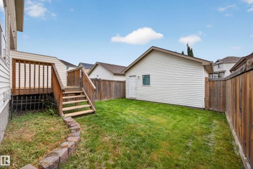 Expansive grassy yard area with a detached structure, wood privacy fencing, and an elevated wood deck with stairs - 483 Watt Boulevard Sw, Edmonton, AB 