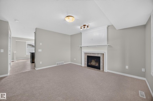 Neutral wall paint, fireplace with a decorative mantel, tiled hearth, recessed lighting, and carpeted flooring - 483 Watt Boulevard Sw, Edmonton, AB 