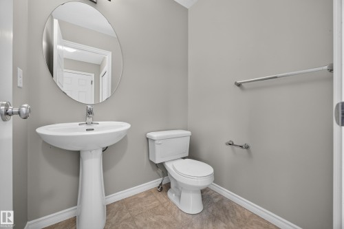 Pedestal sink with chrome faucet, oval wall mirror, toilet, and light gray wall paint - 483 Watt Boulevard Sw, Edmonton, AB 