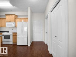Kitchen with wood-finish flooring, light wood cabinetry, and white appliances - 
