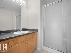Vanity with wood-finish cabinetry, integrated sink, and dark countertop - 