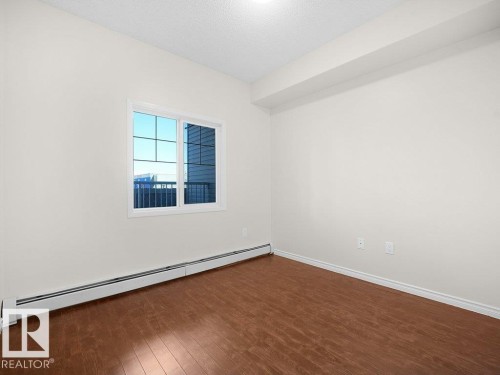 Second Bedroom - Wood-finish flooring, white walls, and a window with a white frame - #116 16807 100 Av Nw, Edmonton, AB 