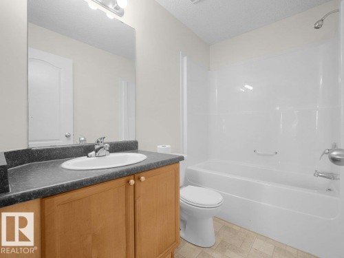 Vanity with wood-finish cabinetry, integrated sink, and gray countertop - #116 16807 100 Av Nw, Edmonton, AB 