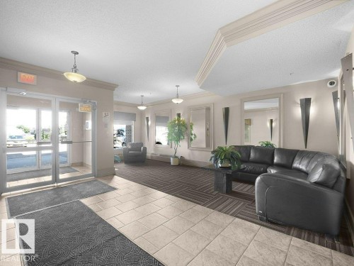 Tiled flooring entry transitioning to carpet, recessed lighting, and wall sconces - #116 16807 100 Av Nw, Edmonton, AB 