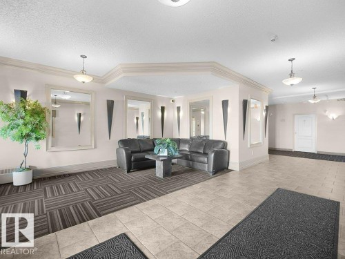 Neutral-toned tile flooring, wall-mounted sconces, pendant lighting, mirrored wall accents, and ceiling crown molding - #116 16807 100 Av Nw, Edmonton, AB 