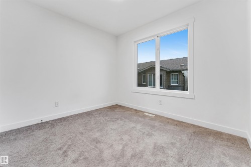 Neutral-toned carpeting paired with white walls, featuring a large window with white trim - #45 2710 66 St Sw, Edmonton, AB 