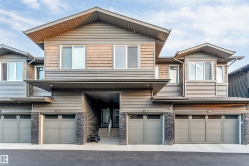 Contemporary townhome exterior featuring multi-toned siding, stone accents, and integrated garage doors - #45 2710 66 St Sw, Edmonton, AB 