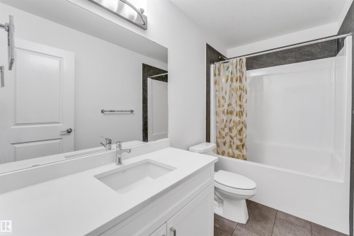 White vanity with an integrated sink and chrome faucet, large mirror, and overhead light fixture - #45 2710 66 St Sw, Edmonton, AB 
