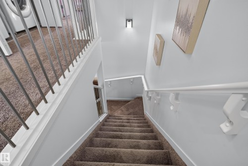 Carpeted staircase with white handrails and modern metal balusters - 17363 120 Street Nw, Edmonton, AB 