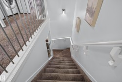 Carpeted staircase with white handrails and modern metal balusters - 