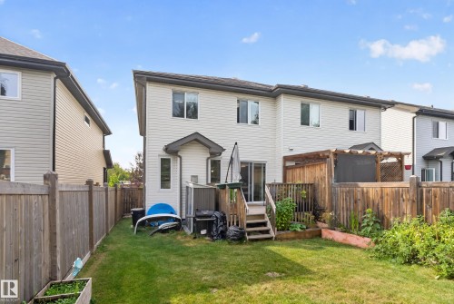 Expansive backyard featuring a manicured lawn, wood fencing, a raised deck, and a wood pergola - 17363 120 Street Nw, Edmonton, AB 