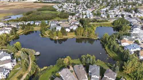 Residential area surrounding a pond with a walking path, mature trees, and nearby open green spaces - 17363 120 Street Nw, Edmonton, AB 