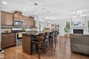 Kitchen featuring stainless steel appliances, dark countertops, wood-finish flooring, and an island with pendant lighting - 17363 120 Street Nw, Edmonton, AB 