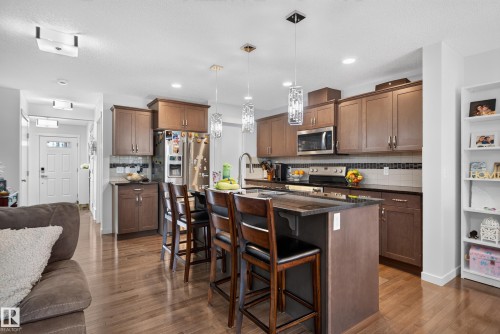 Chef's kitchen featuring rich wood cabinetry, stainless steel appliances, granite countertops, and a center island with seating - 17363 120 Street Nw, Edmonton, AB 