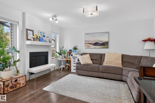 Wood-finish flooring, white walls, multiple windows, a built-in fireplace with a mantel, and a flush-mount ceiling light - 17363 120 Street Nw, Edmonton, AB 