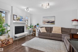 Wood-finish flooring, white walls, multiple windows, a built-in fireplace with a mantel, and a flush-mount ceiling light - 