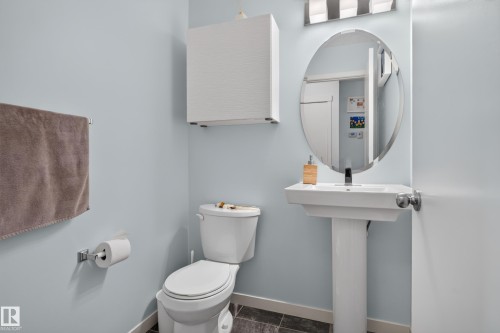 Pedestal sink with an oval mirror, wall-mounted storage cabinet, and chrome fixtures - 17363 120 Street Nw, Edmonton, AB 