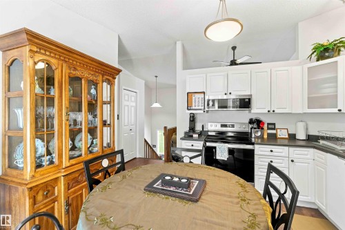Kitchen featuring white cabinetry, dark countertops, a stainless steel microwave, and a built-in range - #6 15 Poirier Av, St. Albert, AB 