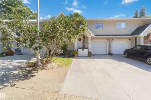 Stucco exterior with multiple dormer windows, a concrete driveway, two single-car garages, and mature landscaping - #6 15 Poirier Av, St. Albert, AB 