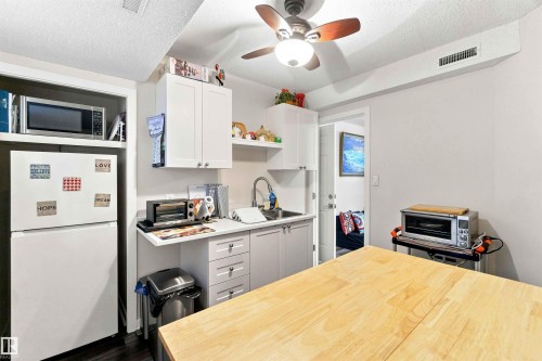 Kitchenette featuring white cabinetry, light countertops, and dark wood-finish flooring - #6 15 Poirier Av, St. Albert, AB 