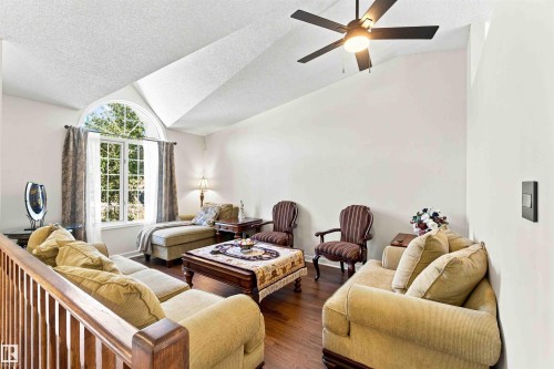 Vaulted ceiling featuring a ceiling fan, arched window, wood-finish flooring, and wood railing - #6 15 Poirier Av, St. Albert, AB 