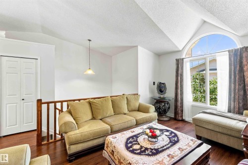 Vaulted ceiling, wood-finish flooring, half-round window, white paneled bi-fold closet door, and wood railing - #6 15 Poirier Av, St. Albert, AB 