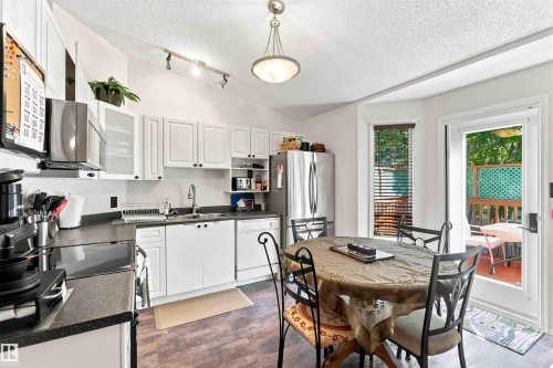 White cabinetry, dark countertops, wood-finish flooring, stainless steel appliances, and outdoor access - #6 15 Poirier Av, St. Albert, AB 