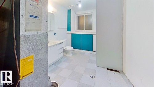 Dual sink vanity with white cabinetry, tile flooring, built-in storage with accent doors, and a window - 4611 52 Avenue, Stony Plain, AB 