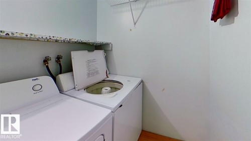 Laundry area featuring wood-finish flooring, wall-mounted shelving, and appliance hookups - 4611 52 Avenue, Stony Plain, AB 