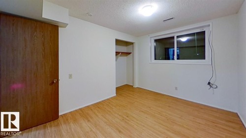 Wood-finish flooring, white walls, built-in closet with shelving, and a bright window - 4611 52 Avenue, Stony Plain, AB 