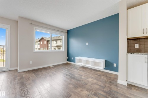 Wood-finish flooring throughout, a large window, and a built-in floating shelf - 3340 15A Avenue Nw, Edmonton, AB 